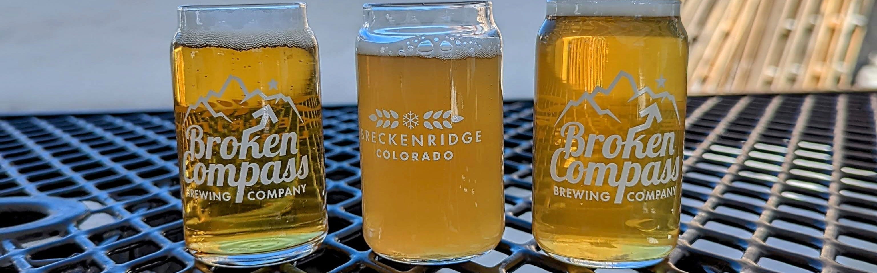 Three glasses of beer sit on a picnic table. 