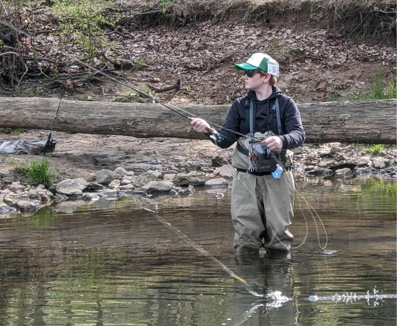 A young angler using the Orvis Clearwater LA II Fly Reel while wading in a river.