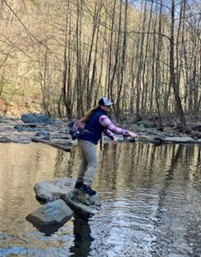 A fisherwoman with the Orvis Guide Sling on while she stands in a river.