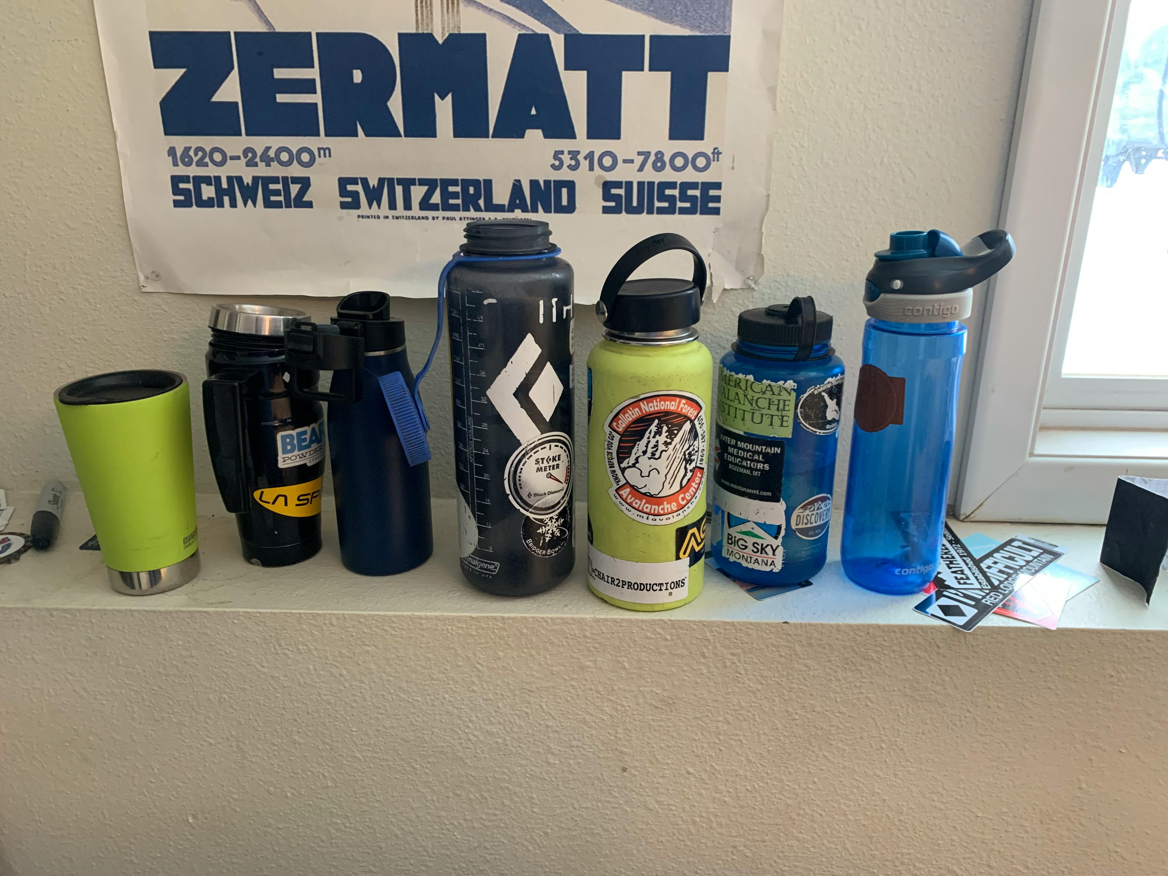 A row of reusable water bottles and thermos containers on a shelf