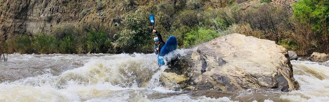 A kayaker navigating over a rock in rapids on Upper Salt River