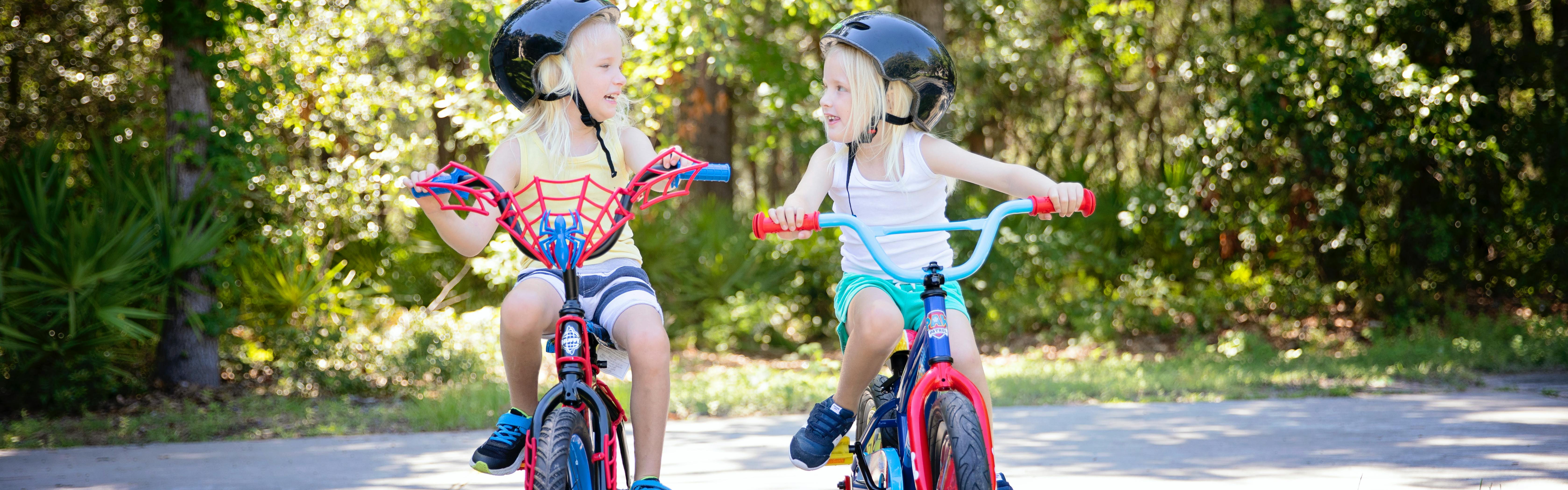 Two young girls riding bikes. 