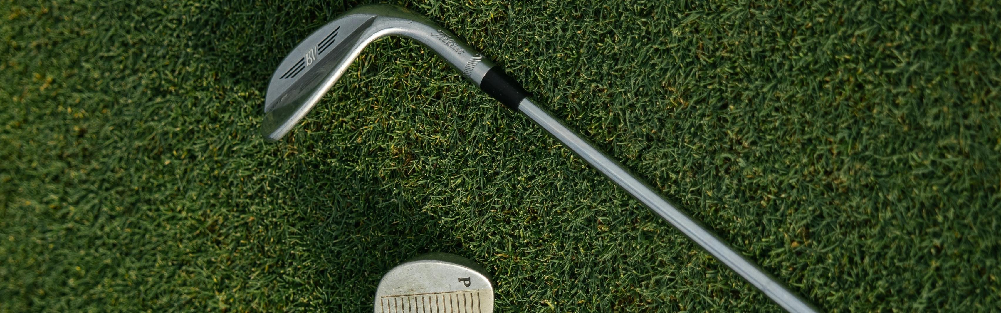 Two golf clubs lying on the grass.