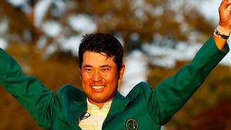 Hideki Matsuyama celebrating his Masters 2021 tournament win in his green Masters jacket and with his arms in the air