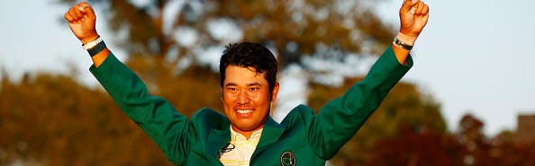 Hideki Matsuyama celebrating his Masters 2021 tournament win in his green Masters jacket and with his arms in the air