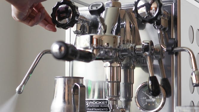 A barista turns a knob on a Rocket Espresso machine.