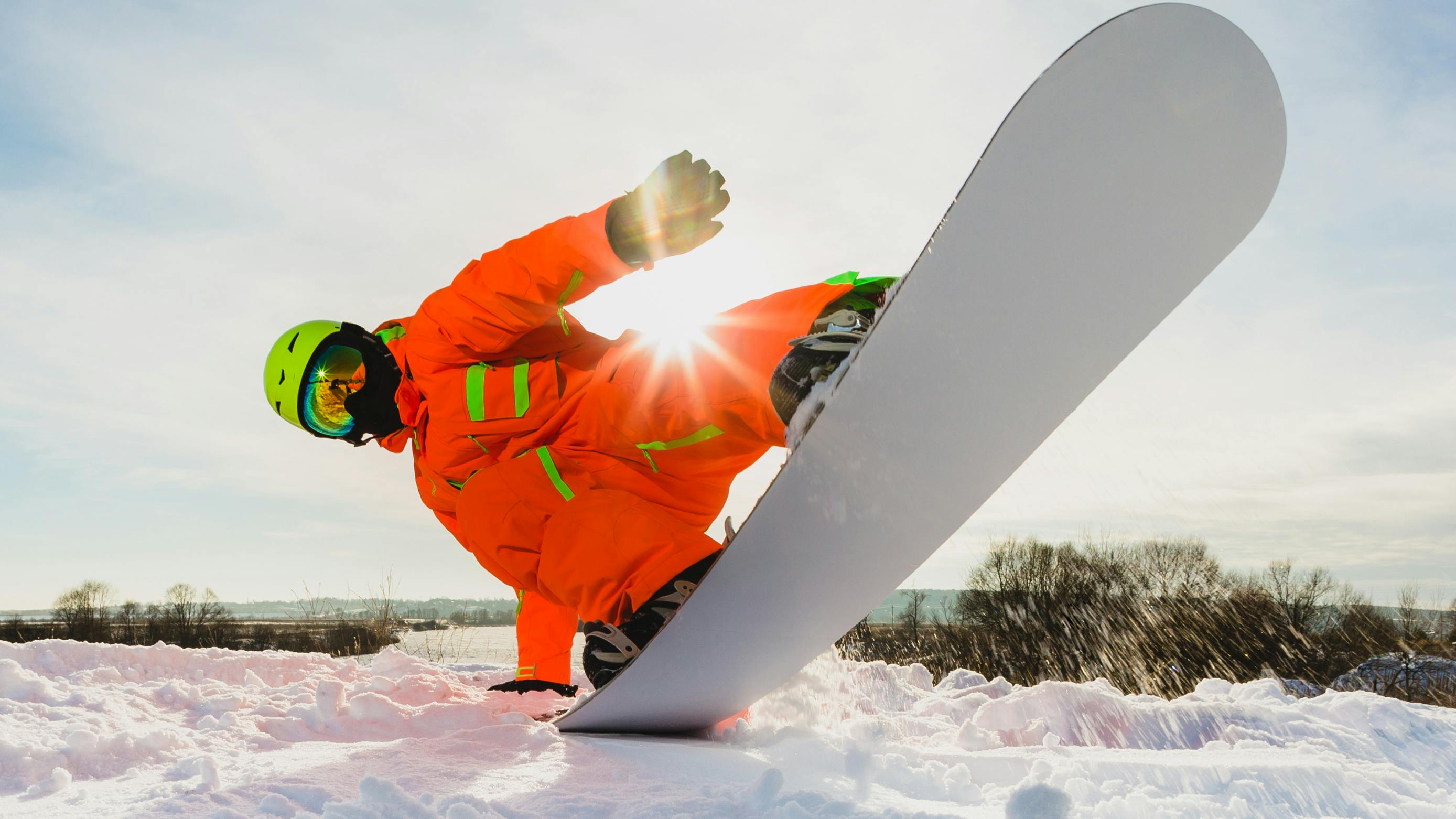 A snowboarder doing a butter trick. 