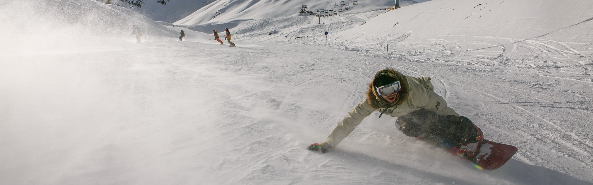 A snowboarder leads a group and executes a turn