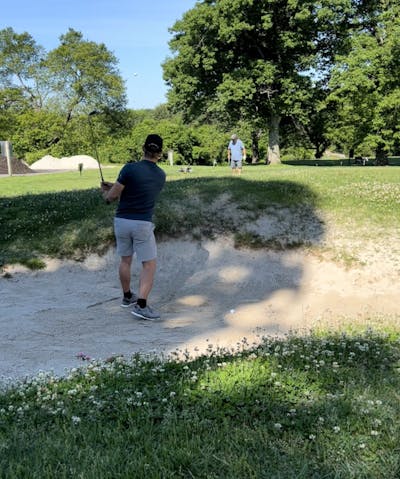 A man is playing a ball out of a bunker with the MG3 club.