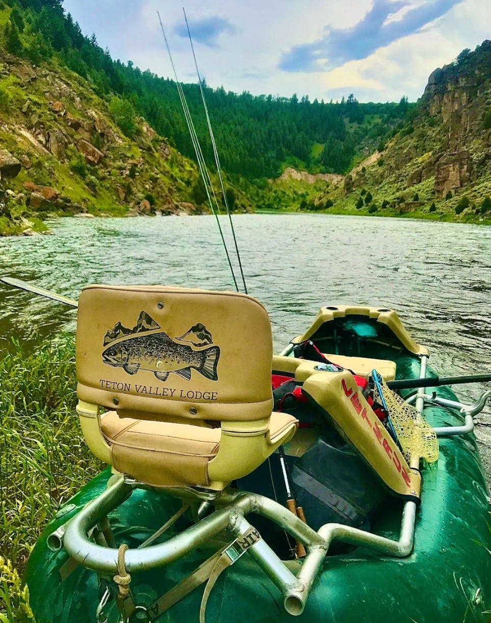 A fly fishing boat with a chair and rod looking down a river. 