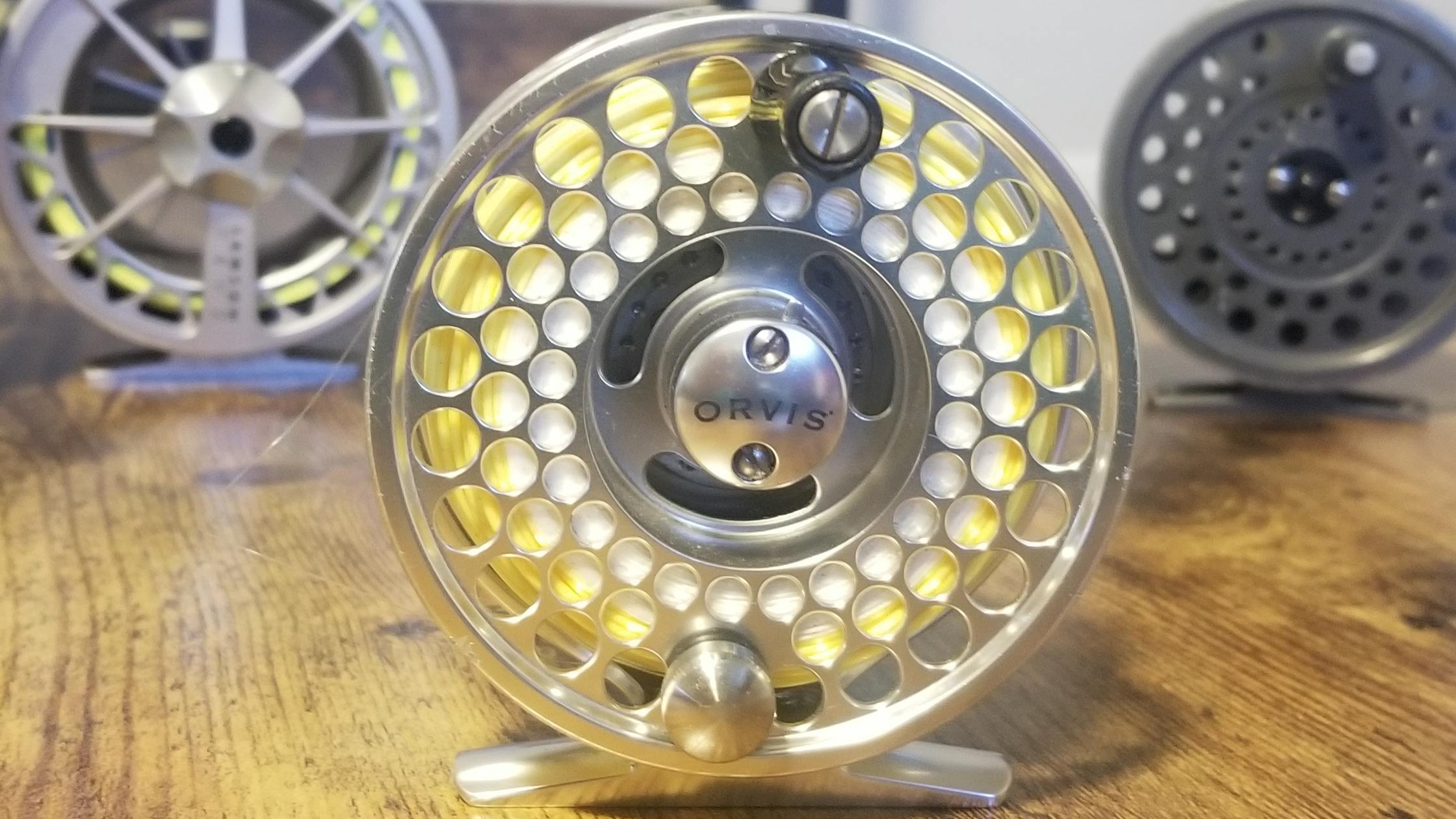 Three fly reels on a wooden table