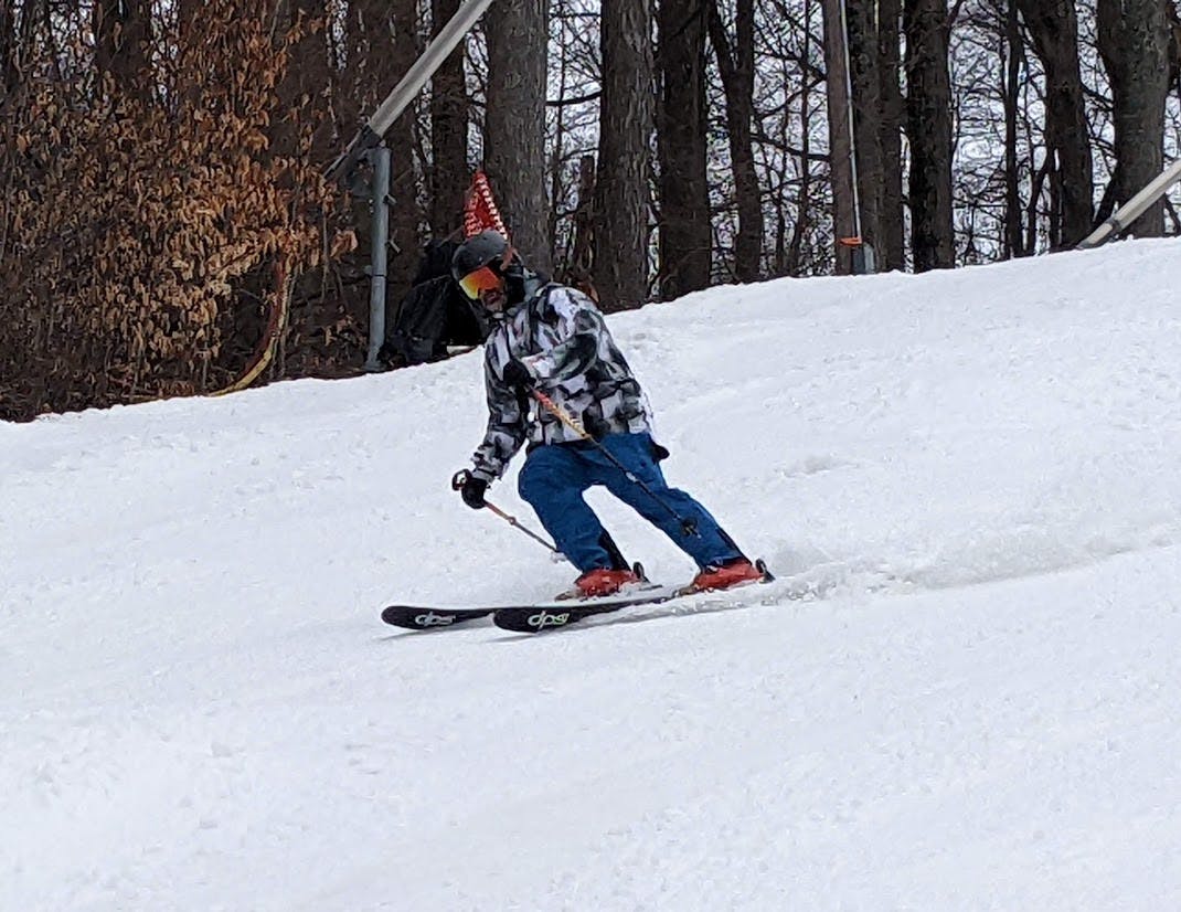 A skier turning down a mountain on the DPS Pagoda 94 C2 Skis · 2023. 