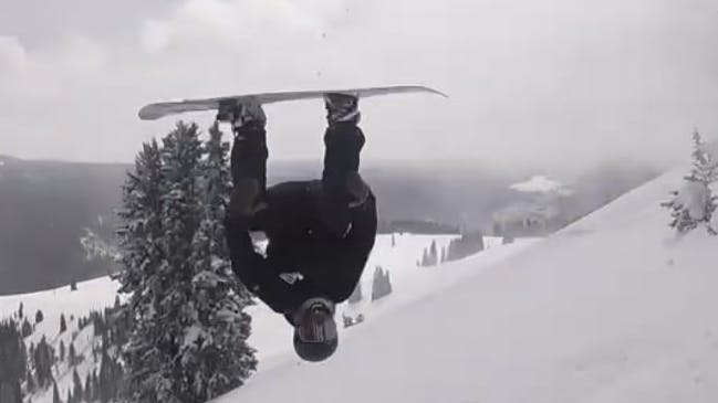 A snowboarder is in the air upside down.