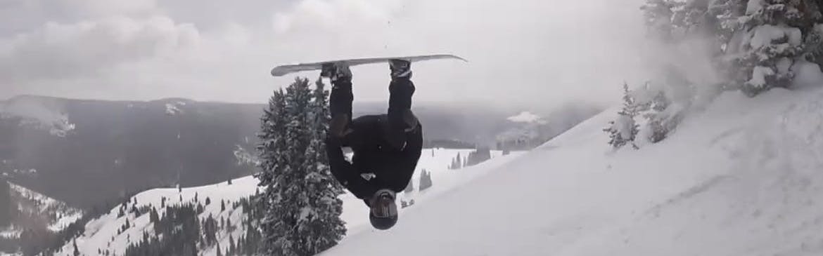 A snowboarder is in the air upside down.