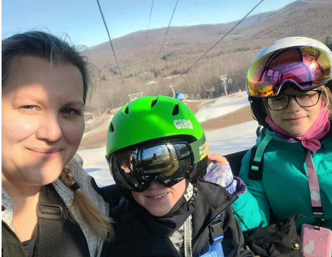 A mom and her two kids in a gondola at a ski resort. 
