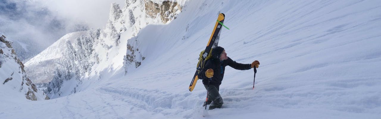 A skier hikes up a couilor with skis on their back.