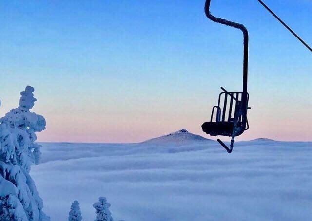 A chairlift high up over the clouds at sunrise.