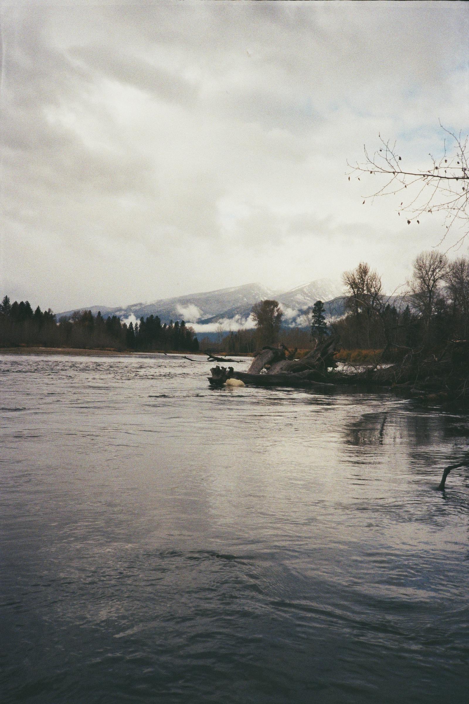 A peaceful, wintery river scene with mountains in the distance