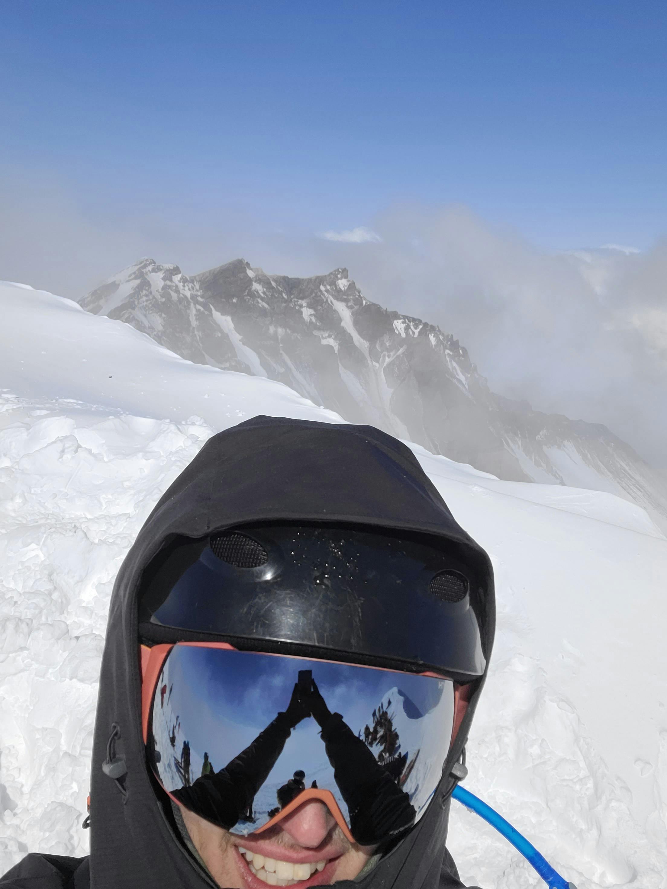 A man wearing the Smith I/O MAG Goggles at the top of a snowy mountain. 