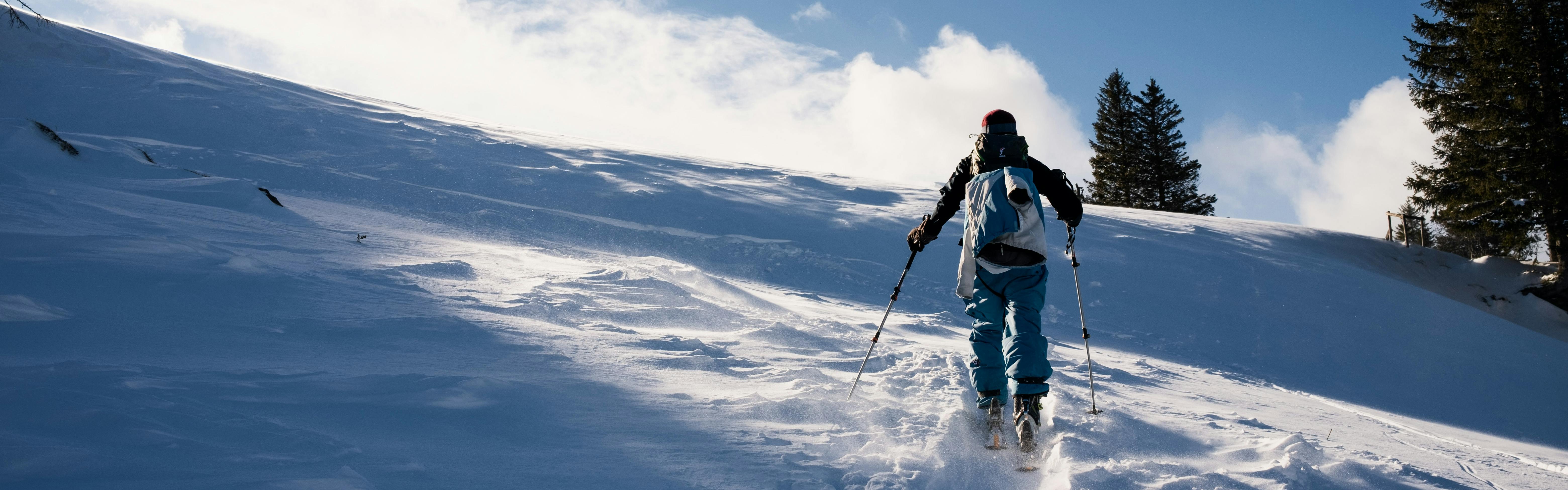 A skier walking up a snowy path. 