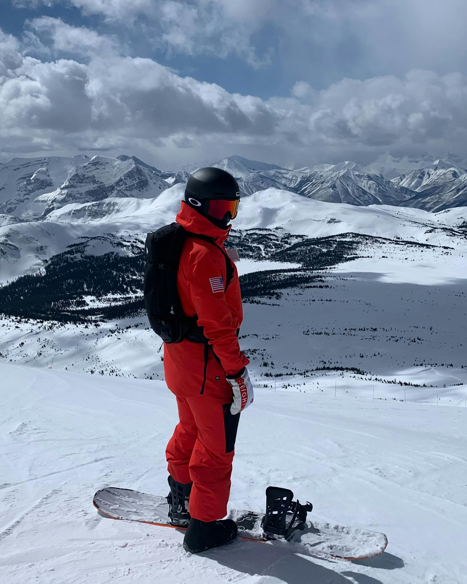 A snowboarder standing at the top of a ski run. 