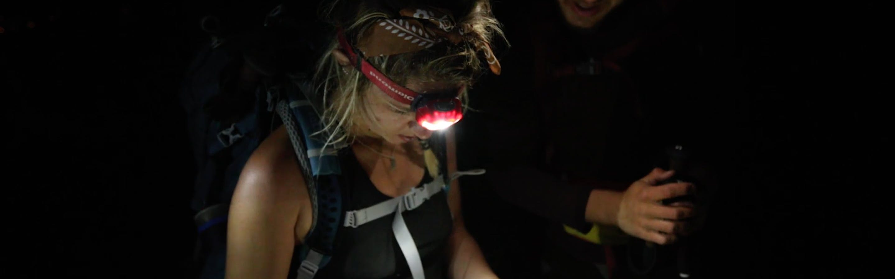 Two campers looking at a map together with their headlamps. 