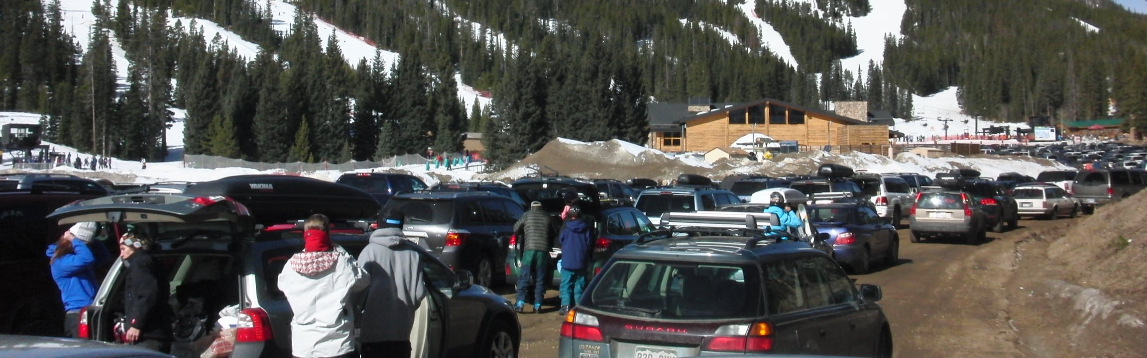 Several skiers getting ready for skiing in the parking lot of a ski resort. 
