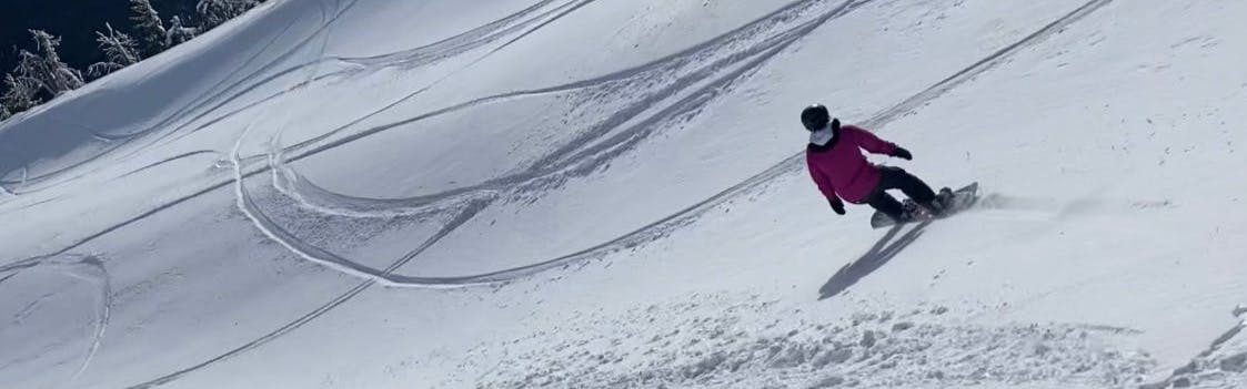 A woman snowboarding down a snowy run. 
