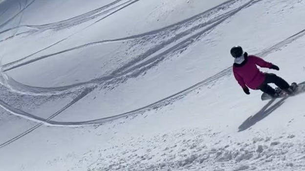 A woman snowboarding down a snowy run. 