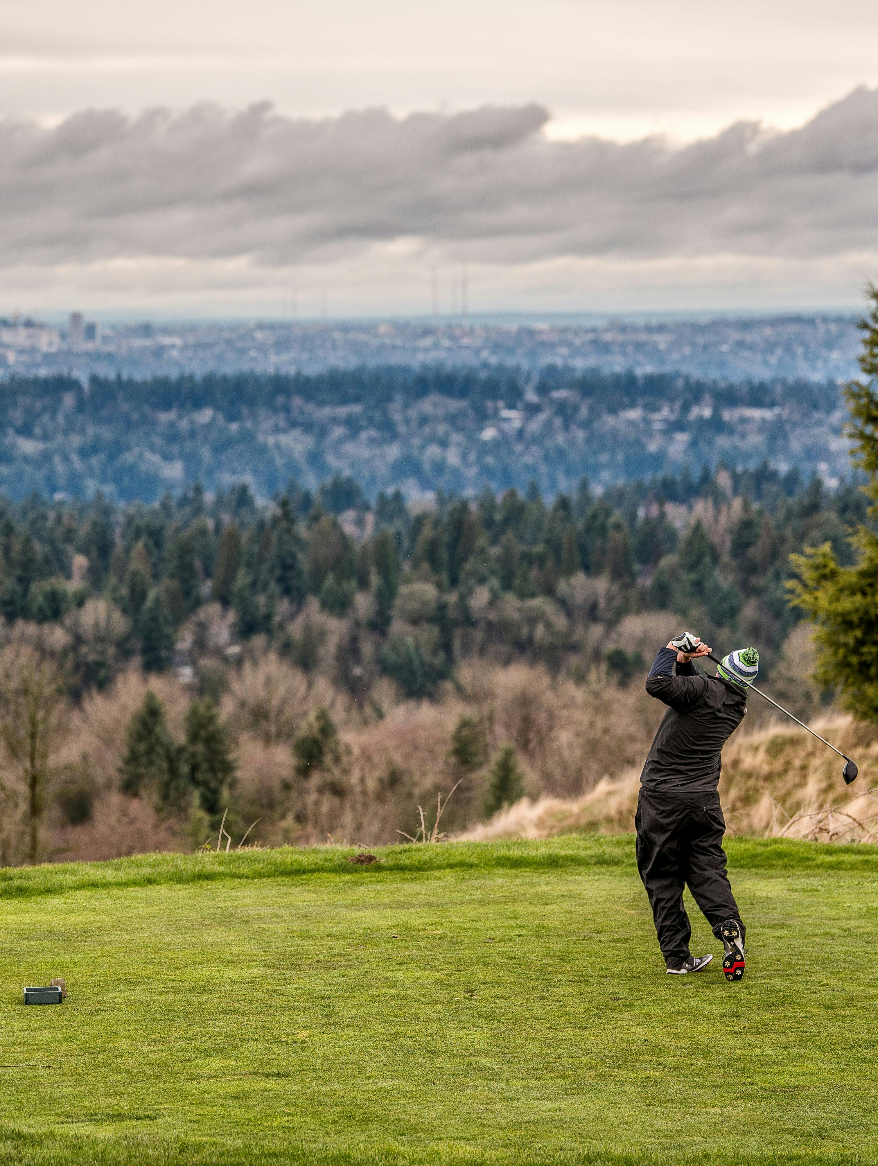 A man swings back his golf club on a course in the winter.