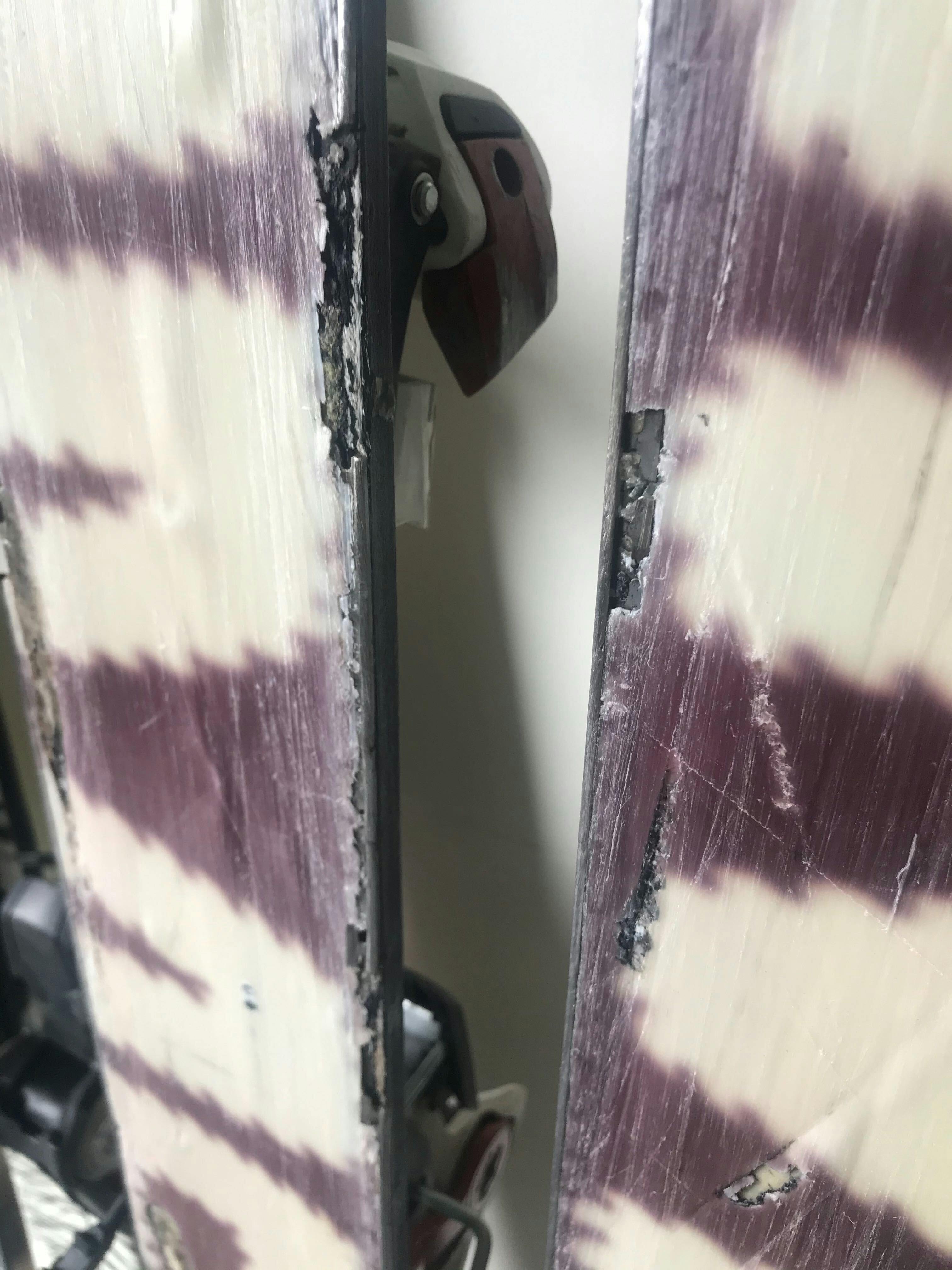 A pair of broken down purple and white skis