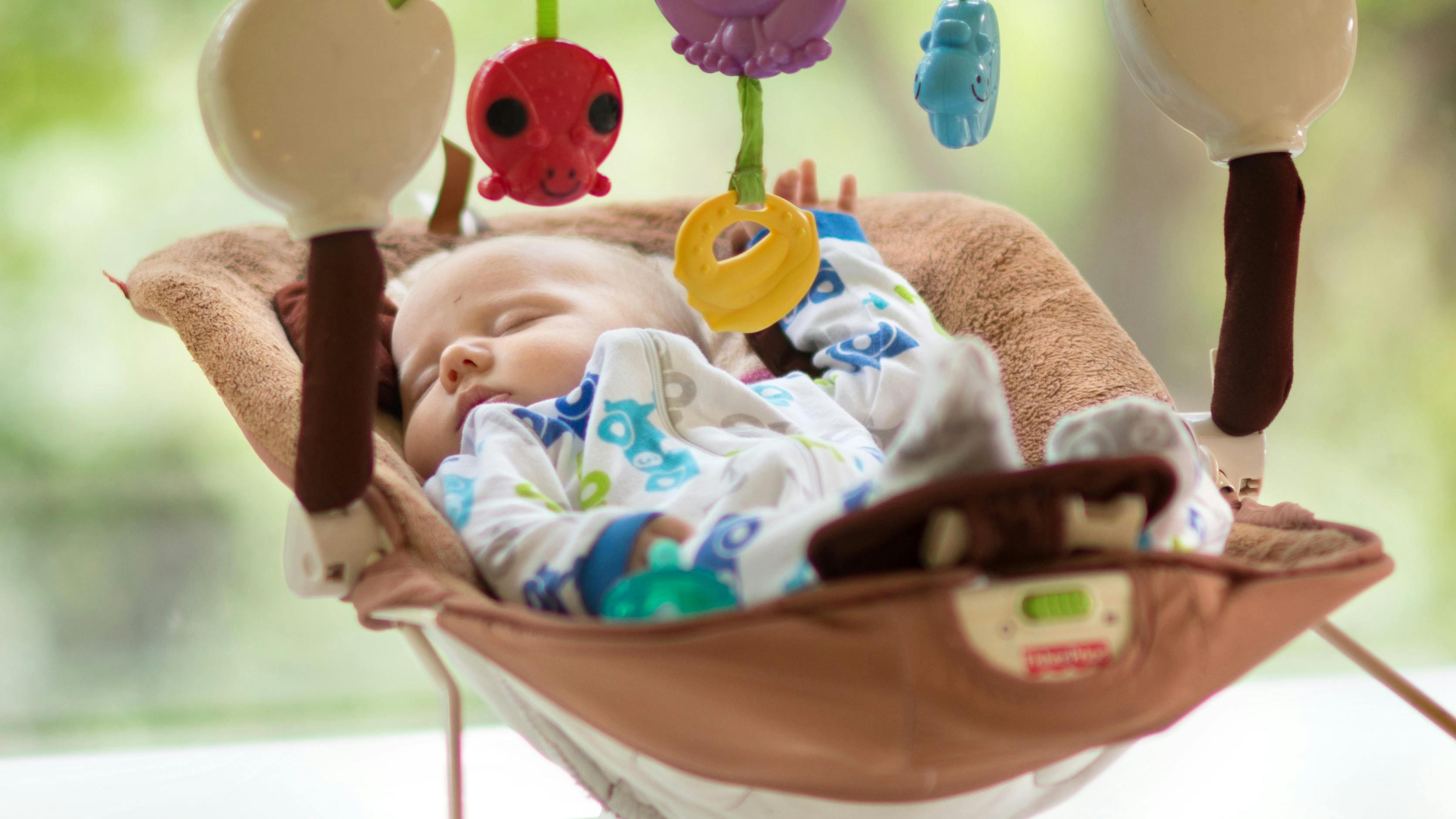 A baby sleeping in a bouncer.