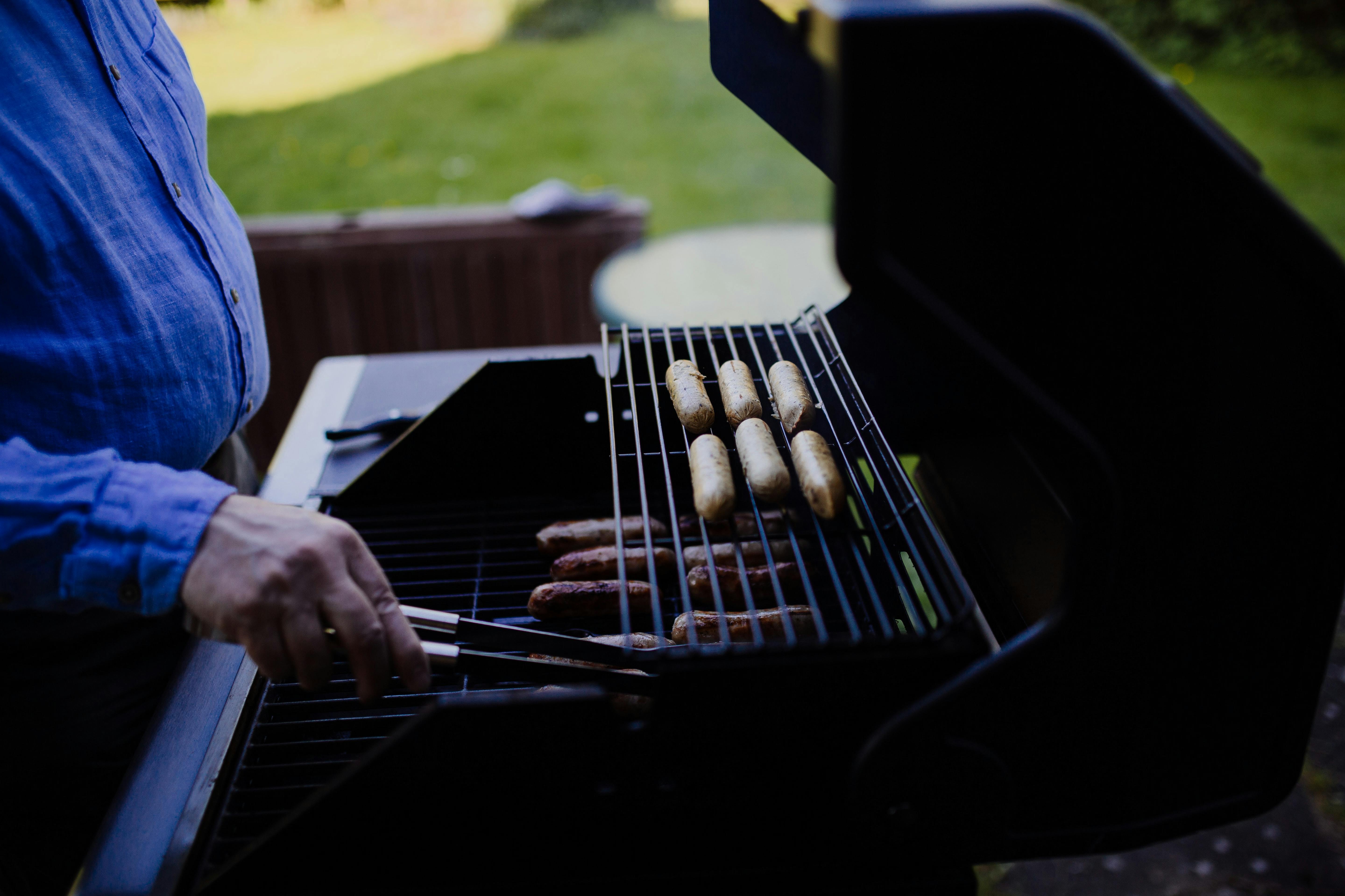 A man moves some things around on a grill. 