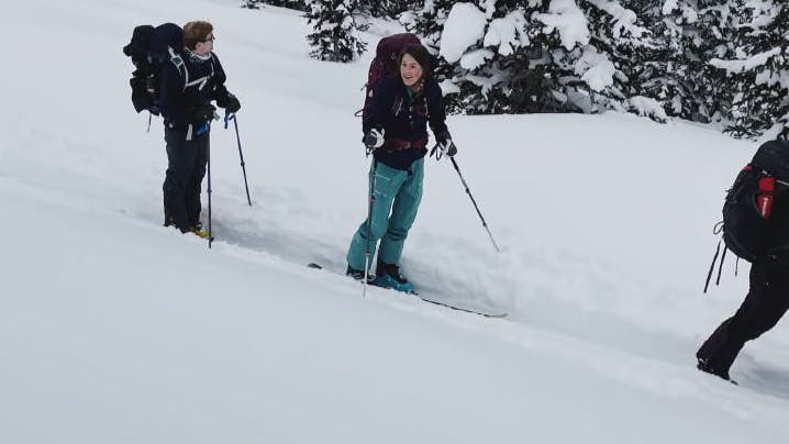 Three skiers walking on a ski skin track with their backcountry skis. 