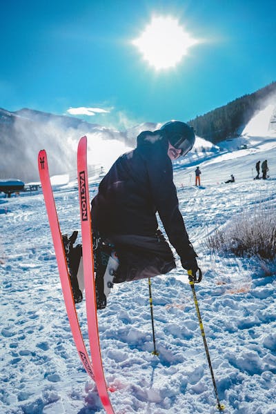 A skier sitting on his skis at the bottom of a ski run. 
