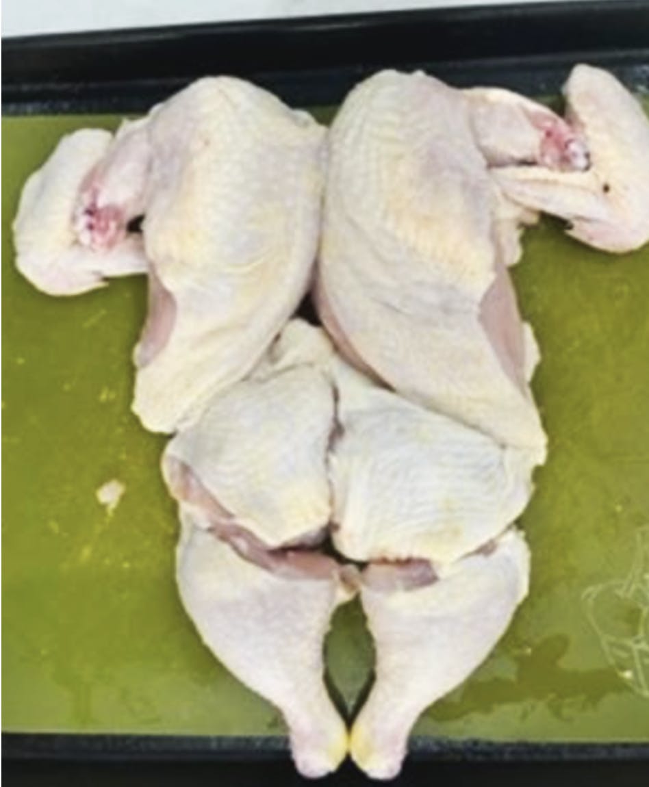 A photo of a chopped up raw chicken in different pieces. 