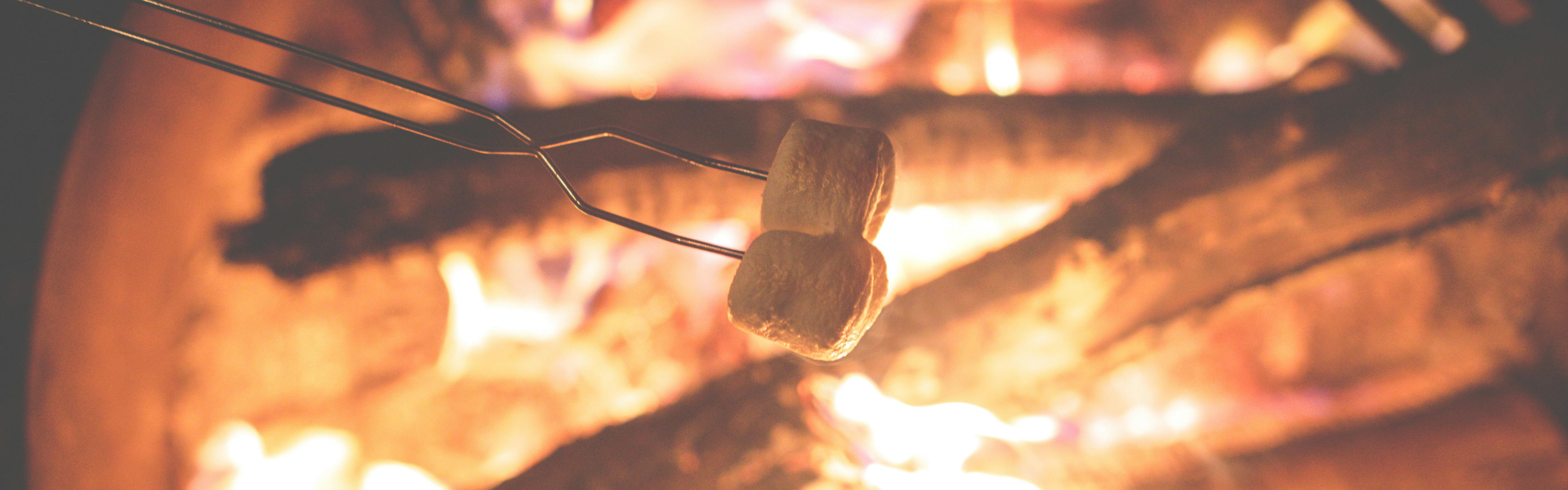 Two marshmallows roasting over a campfire