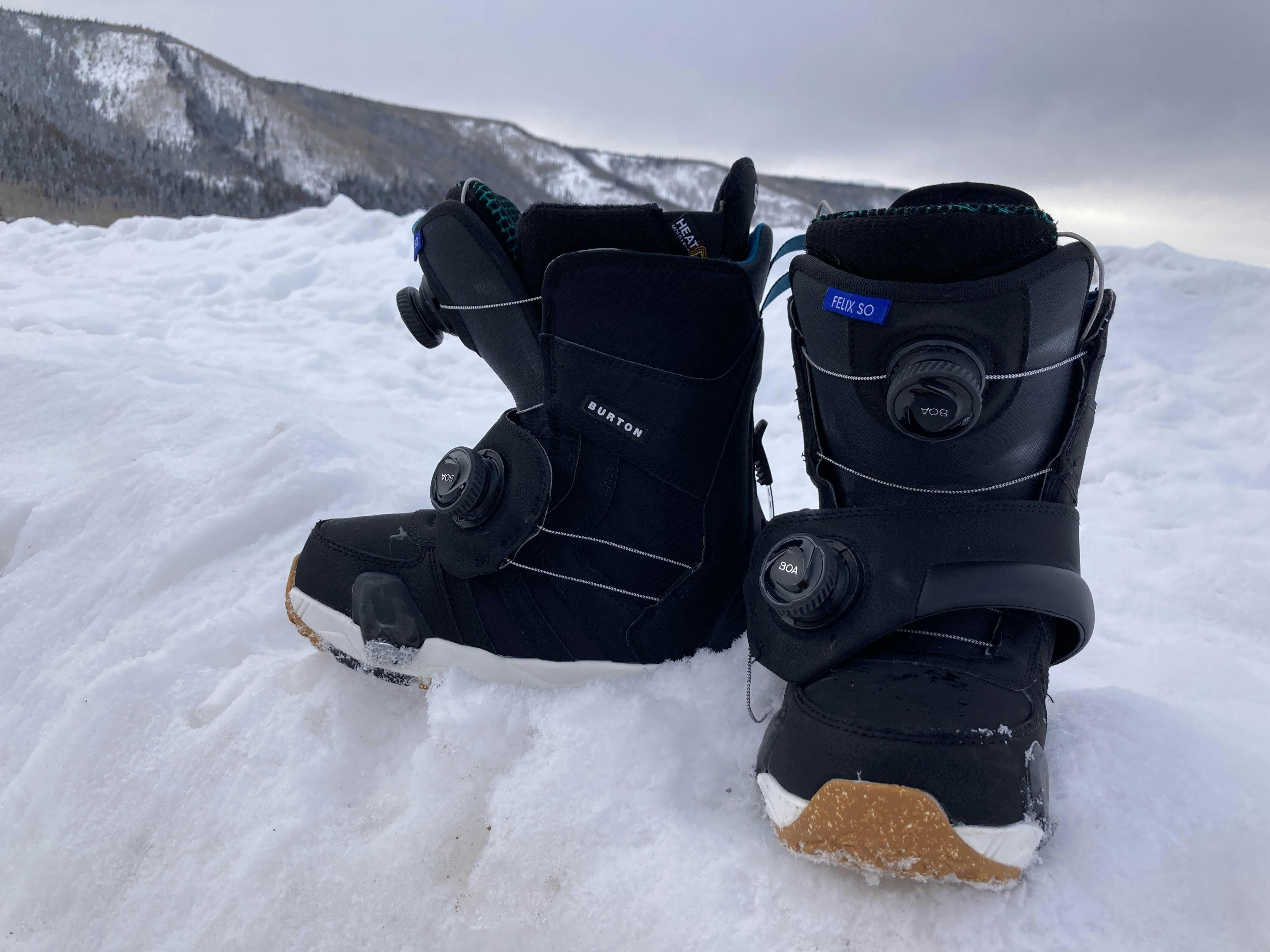 Two black Burton Felix StepOn boots on a snowbank with snowy mountain in the background.