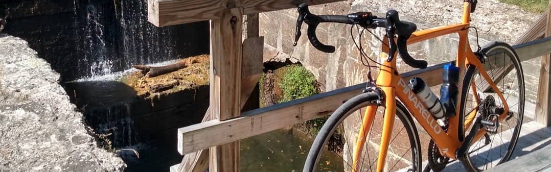 A bike with a clincher tire on it leaning next to a rail on a bridge. 
