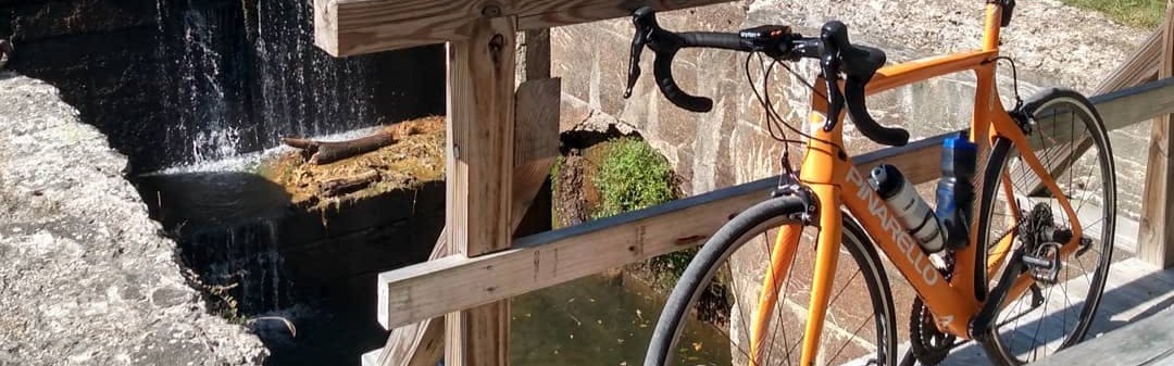 A bike with a clincher tire on it leaning next to a rail on a bridge. 