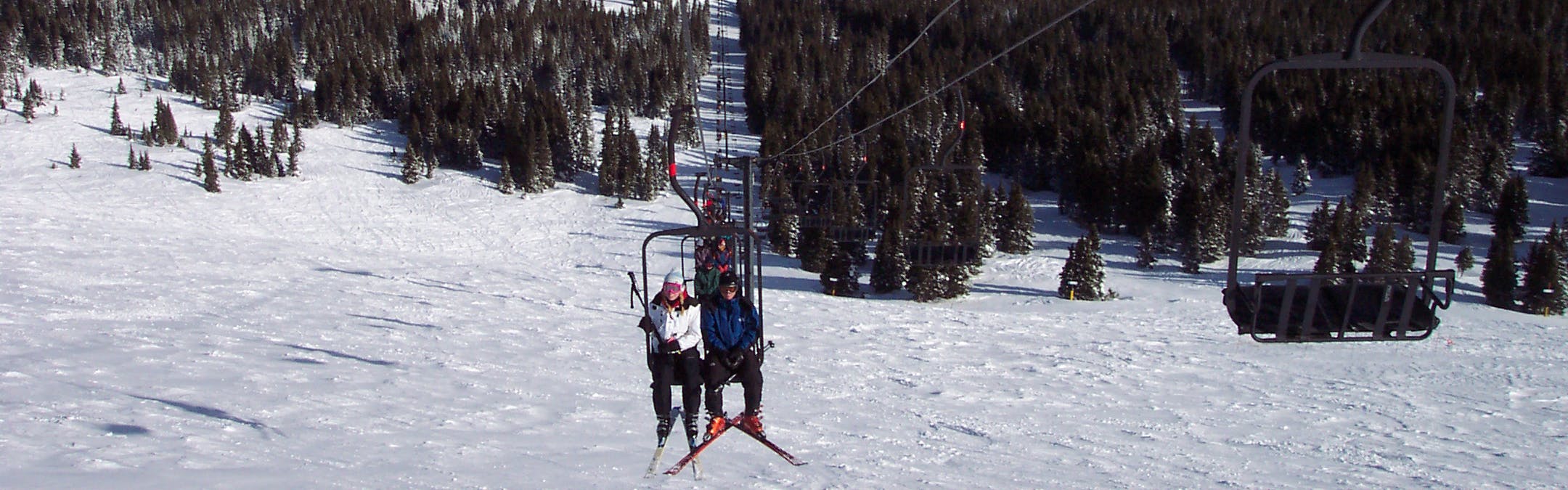 Several skiers sitting on a chairlift at a ski resort. 