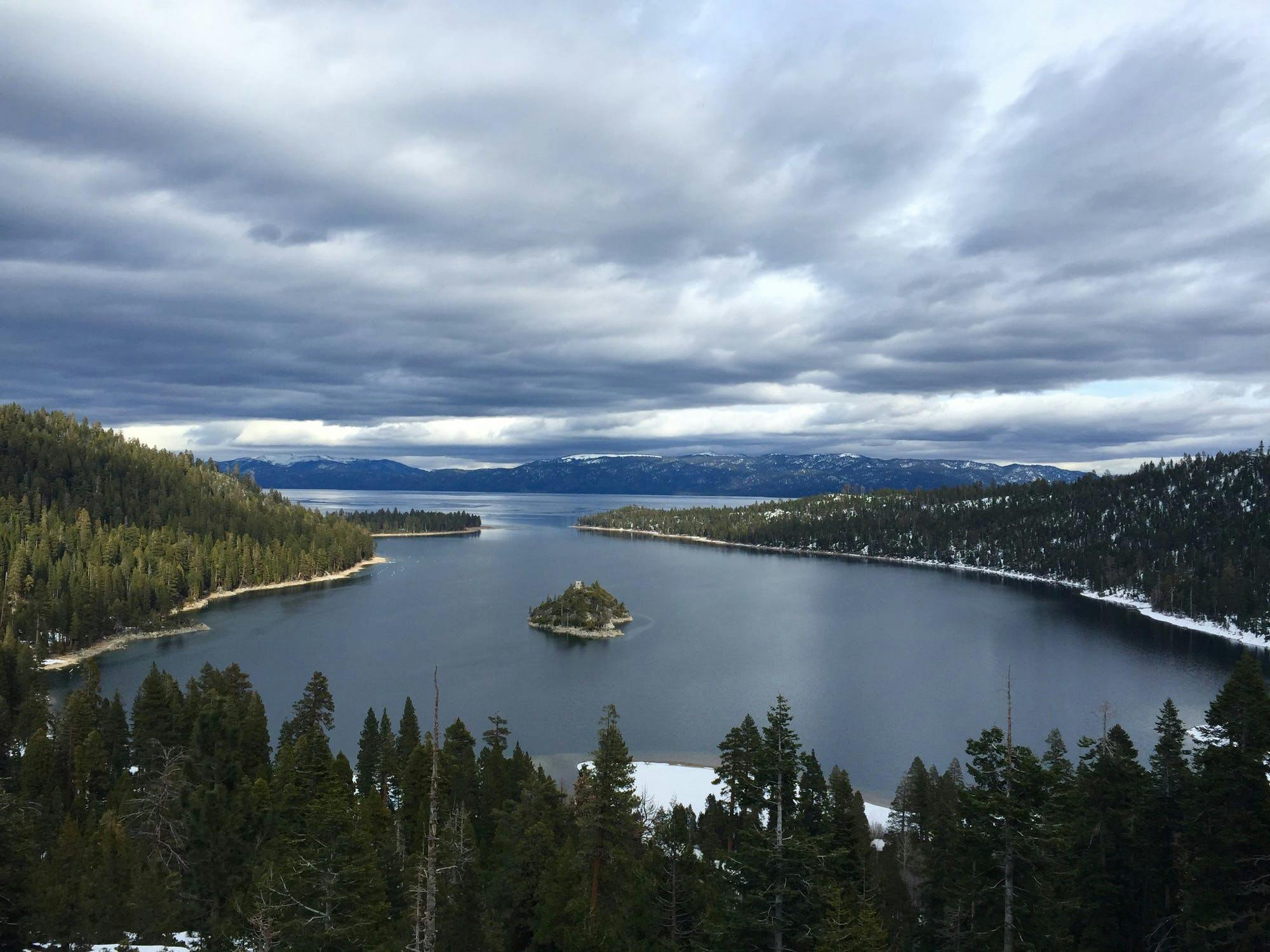A view of Lake Tahoe with trees on the banks and a small island in the middle