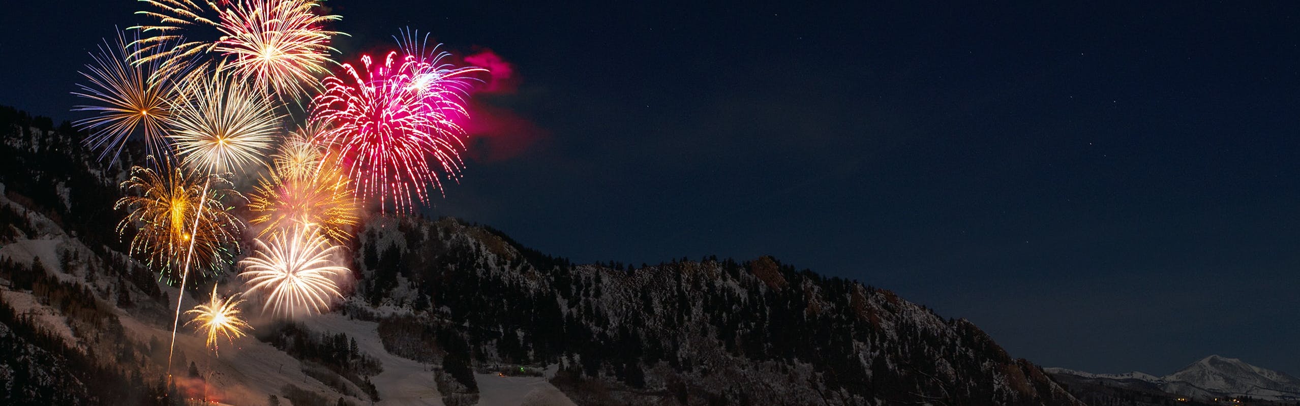 Fireworks explode over a ski resort. It is dark at the ski resort.