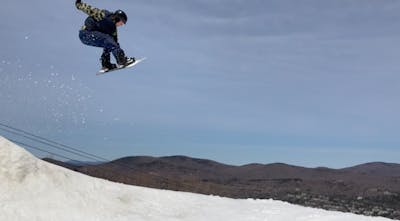 A snowboarder hitting a jump on the Rome Party Mod Snowboard.