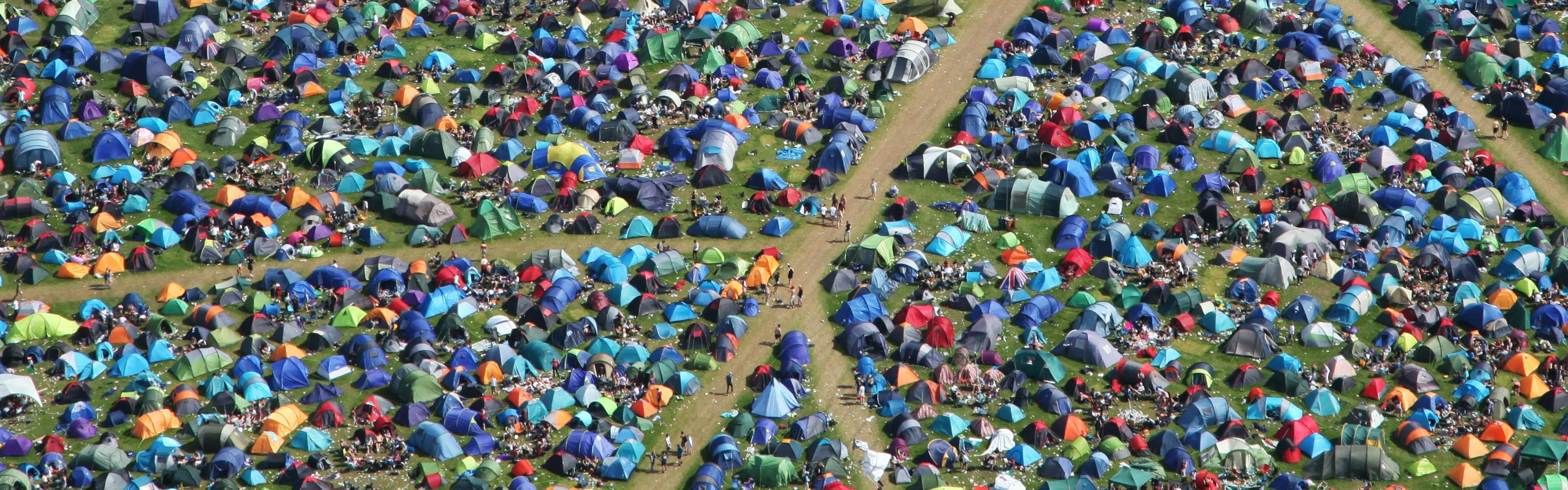 An aerial shot of the ground below absolutely covered in tents with a few well-worn paths cutting through the throng. 
