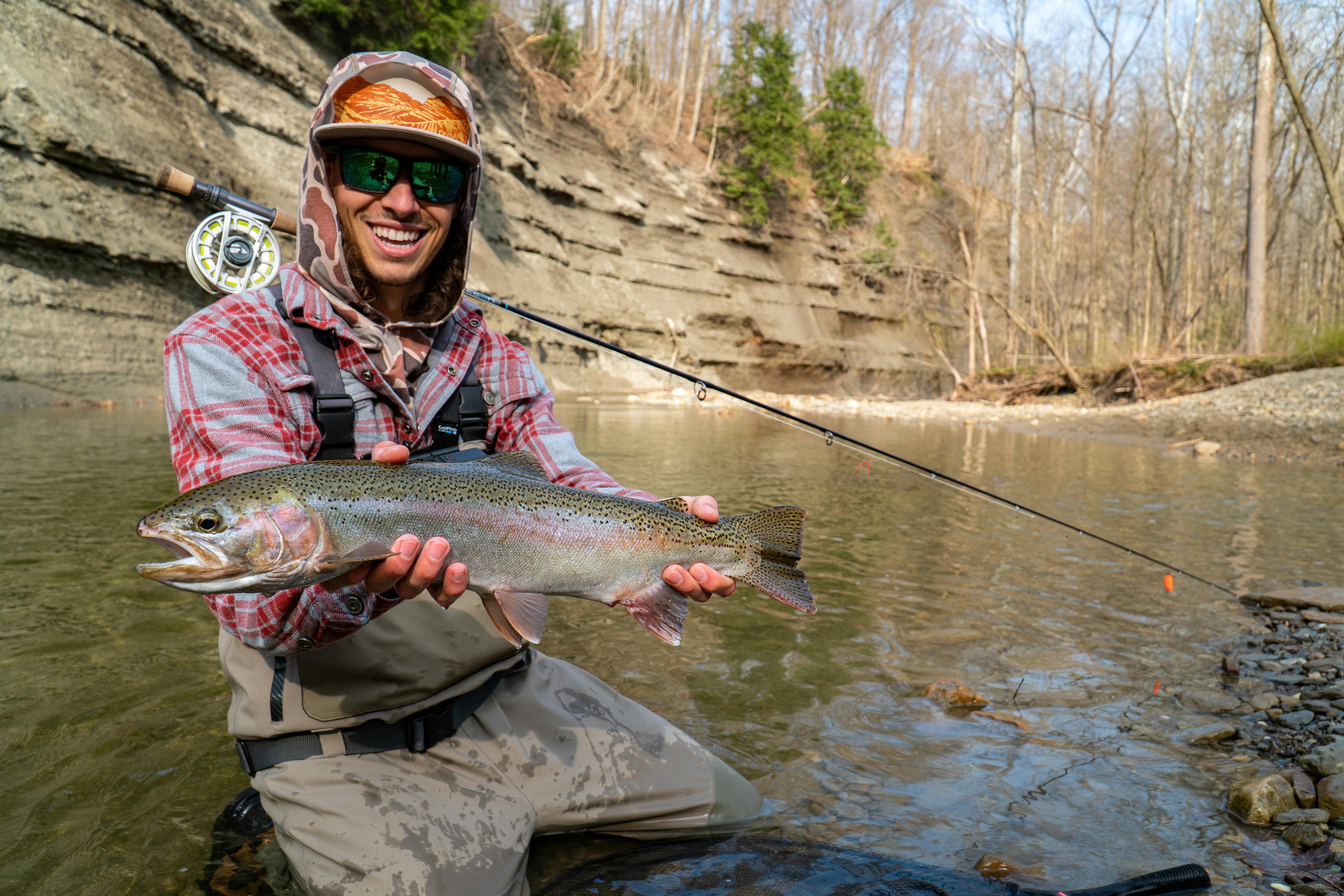 A man holding a fish with the Orvis Hydros Fly Reel on his neck.