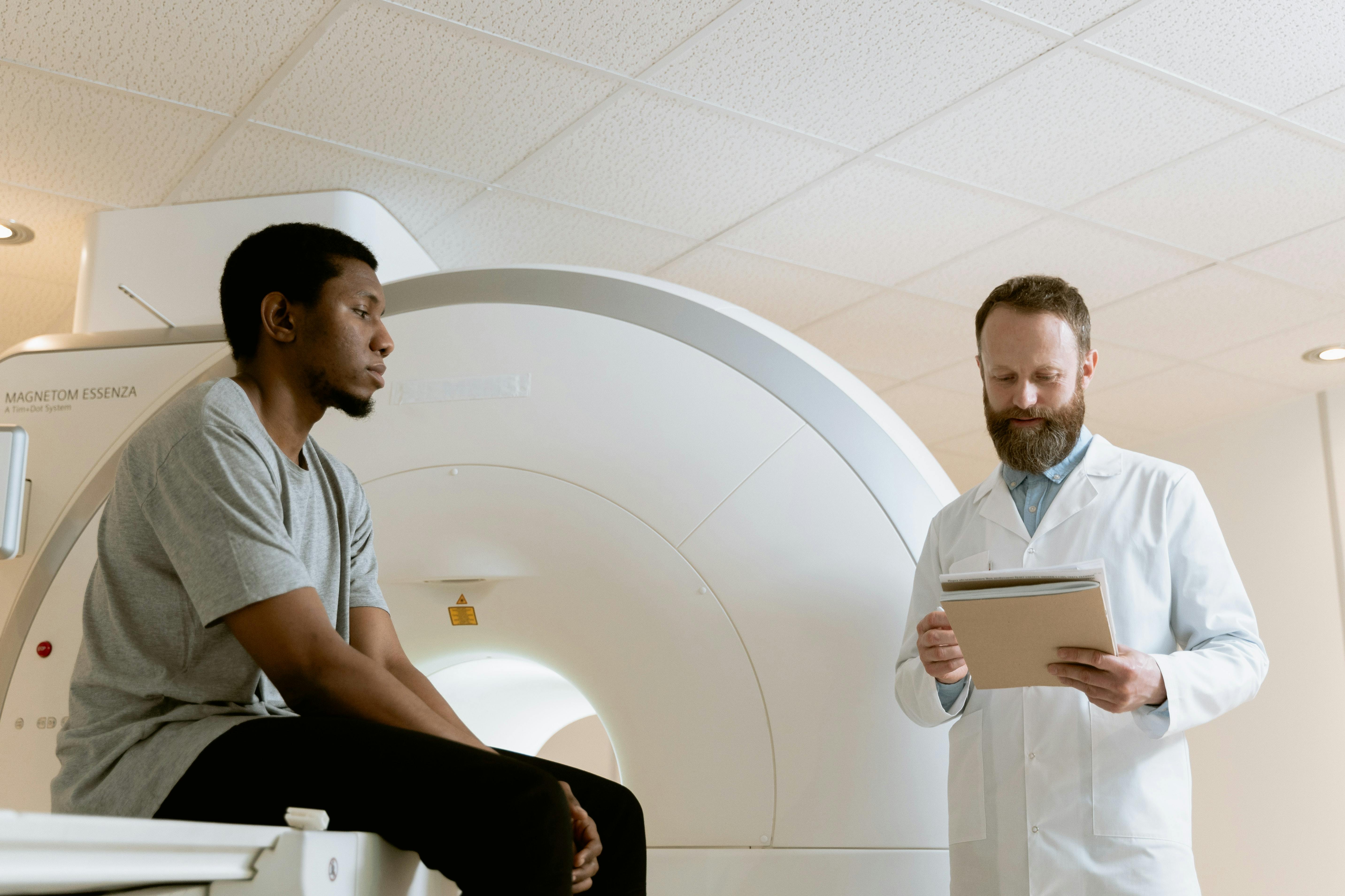 A doctor talking to a man in front of an MRI machine.