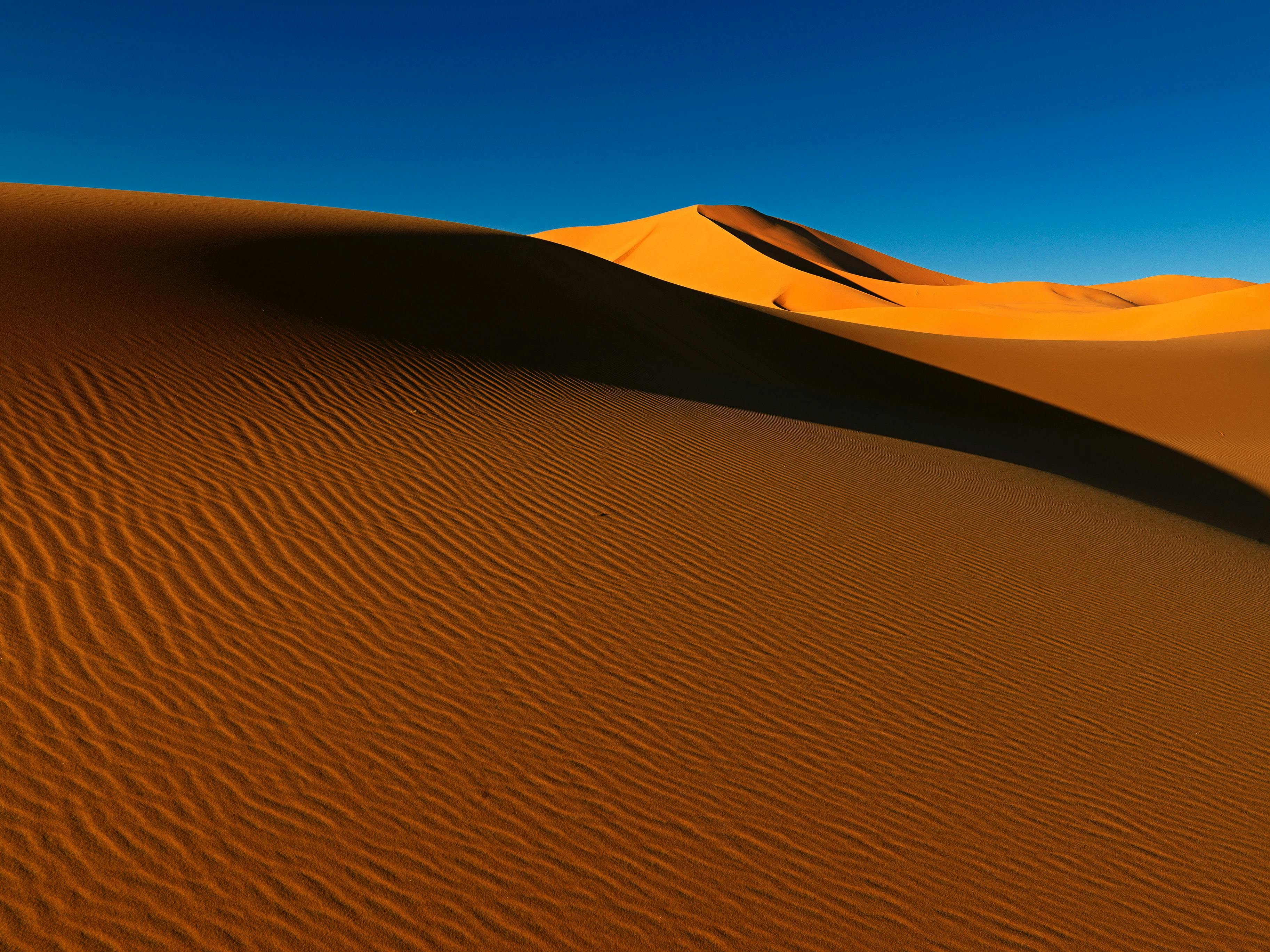 Bright orange sand dunes against a bright blue sky