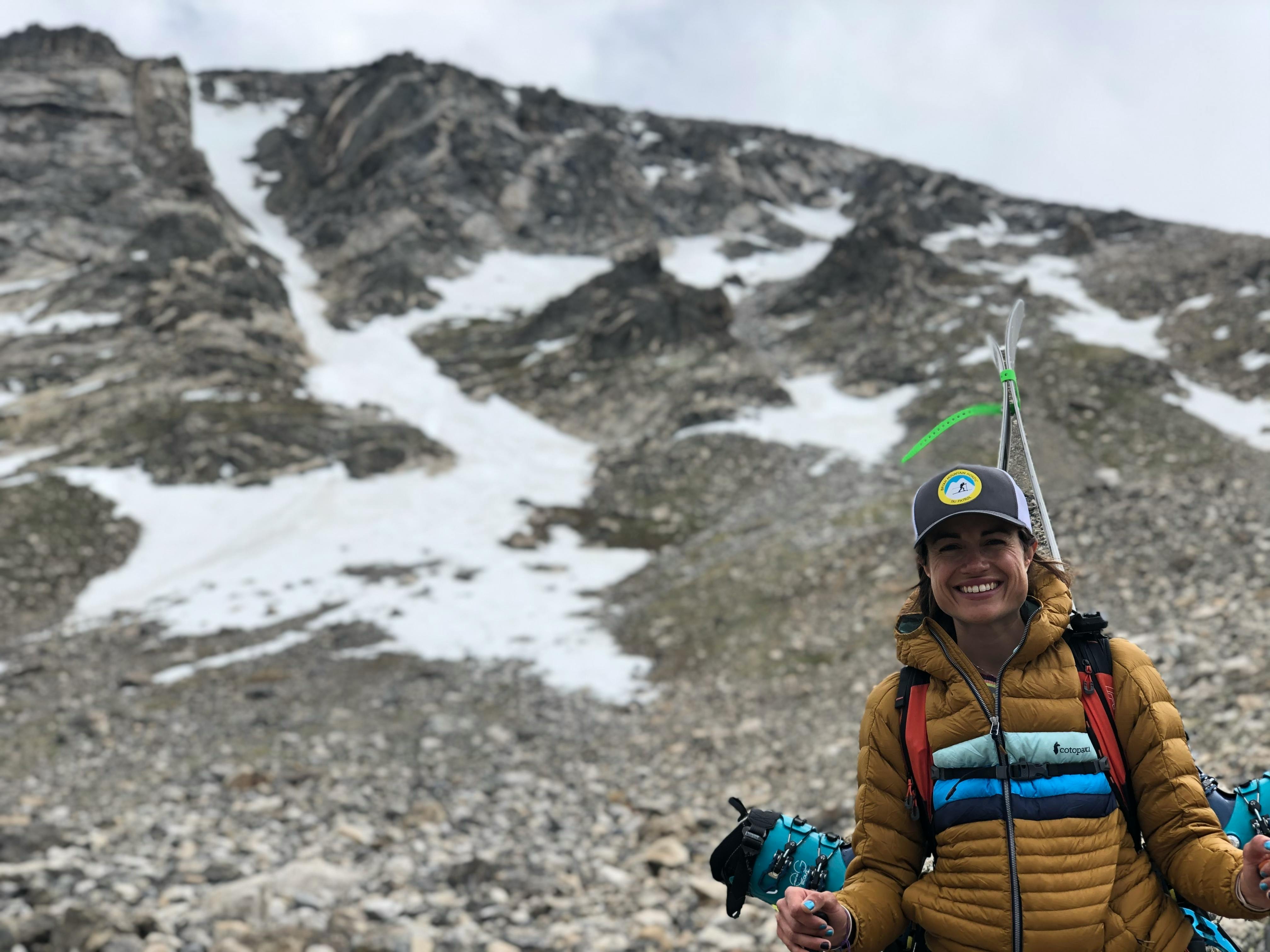 Woman smiling in front of a rocky mountain background.