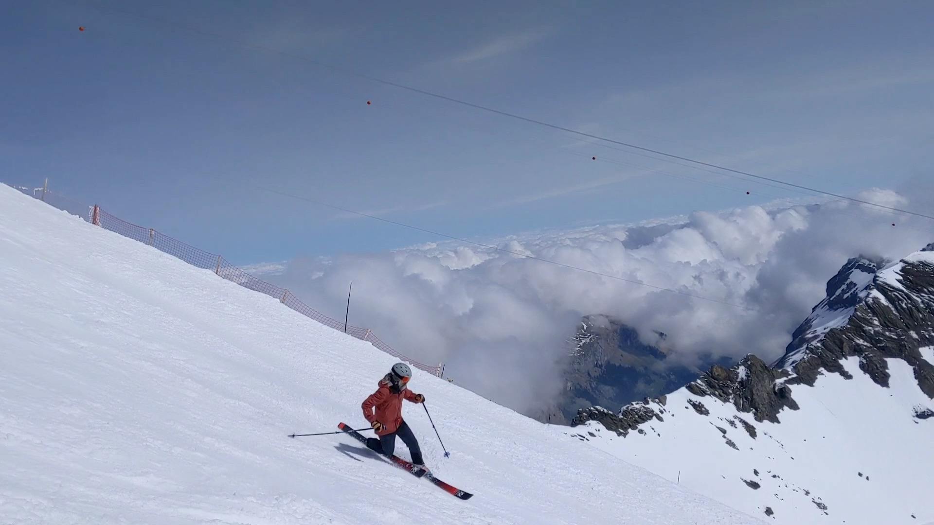 A telemark skier turns down a mountain. There are clouds in the background.